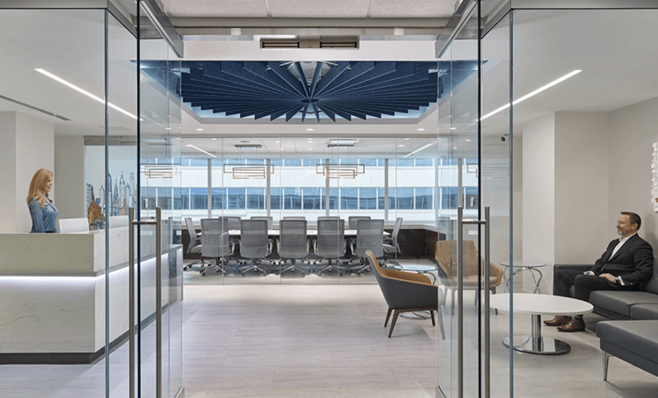 Modern office with a glass entrance, reception desk, waiting area, and a large boardroom in the background.